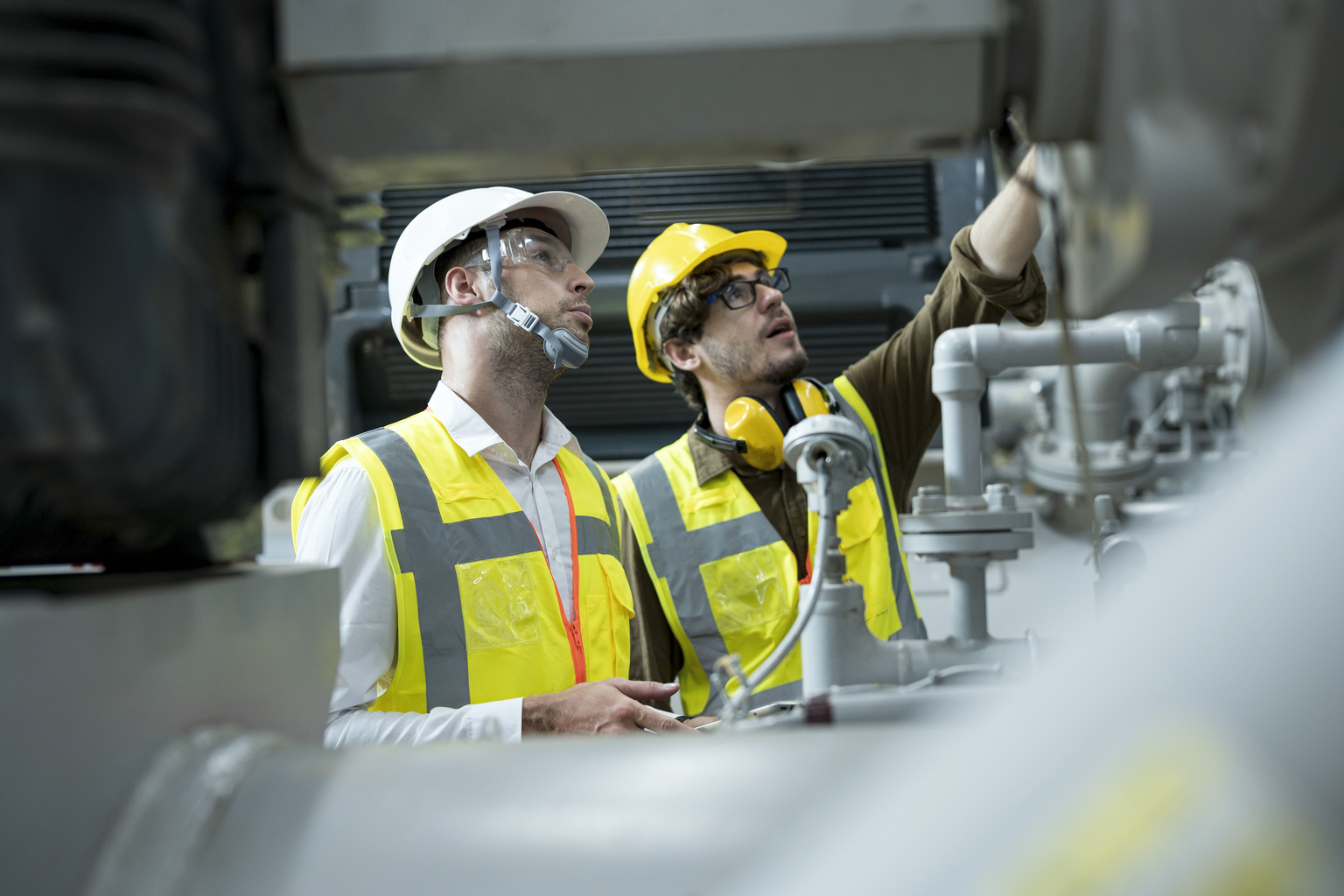 Service engineer explaining to businessman about the HVAC system (Heating, Ventilation and Air Conditioning) in control room shop floor of factory