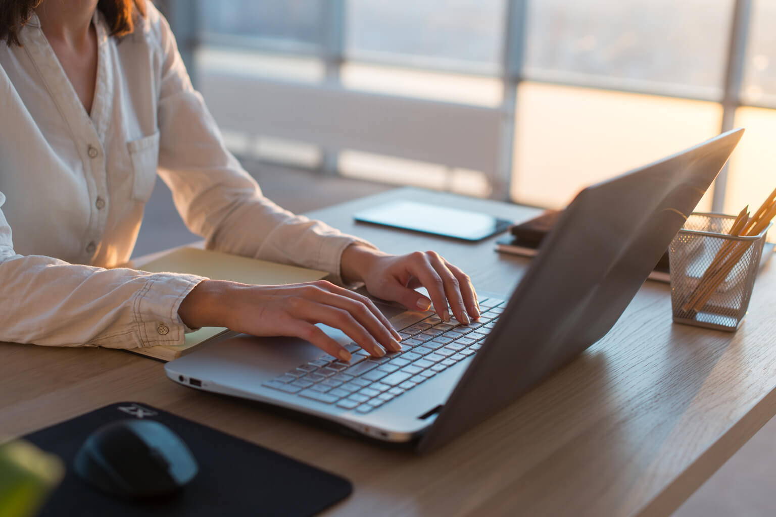 A woman with her hands on the keyboard of a laptop, using CCH ProSystem fx Fixed Assets